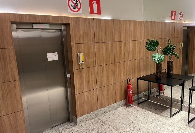 Área de acesso com elevador e decoração em madeira